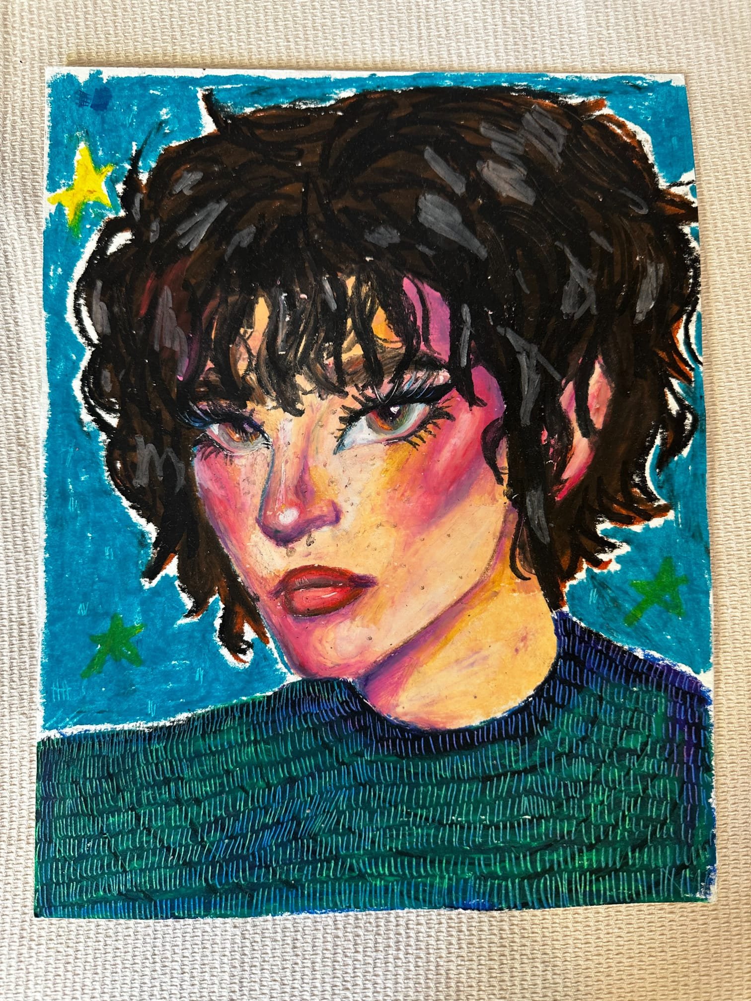 Autorretrato pintado à mão pela Gabriela: rosto de olhar firme, cabelo escuro, sobre fundo azul com estrelas